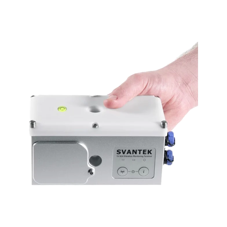 Hand holding a Svantek SV 804 Wireless Triaxial Vibration Monitor on a white background